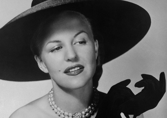 12 Jun 1949, New York, New York, USA --- Dramatic black accessories lend the proper glamorous touch to warbler Peggy Lee's dinner ensemble.  To a sheer, strapless gown, Peggy adds a wide-brimmed Milan hat and suede gloves with intricately-cut gauntlets.  Choker pearls with rhinestone pendant complete the sophisticated costume. --- Image by © Bettmann/CORBIS